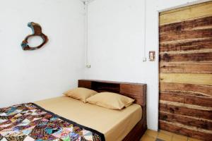 een slaapkamer met een bed met een houten hoofdeinde bij Rumah Kita BnB in Yogyakarta