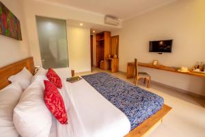 ein Schlafzimmer mit einem großen Bett mit roten und blauen Kissen in der Unterkunft Jani's Place Cottage by Purely in Ubud