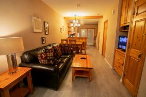 a living room with a leather couch and a table at Banff National Park Wood lodge in Canmore