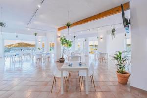 uma sala de jantar com mesas e cadeiras brancas e o oceano em Il Gabbiano em La Maddalena