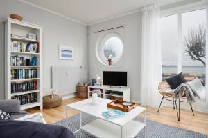 a white living room with a couch and a tv at Windjammer Eagle in Laboe
