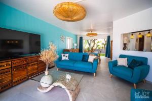 a living room with two blue couches and a tv at Villa Rosaya in Saint-Pierre