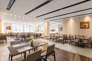 広州市にあるGHIC The Mulian Hotel of Bio-island Guangzhouの建物の中にテーブルと椅子があるレストラン