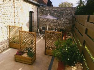 un patio con mesa, sombrilla y algunas plantas en Gîte Beaune-la-Rolande, 3 pièces, 4 personnes - FR-1-590-114, en Beaune-la-Rolande
