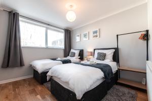 a bedroom with two beds and a window at BEST PRICE! - 1 MIN TO THE SHOPS, BARS, PUBS & RESTAURANTS! PERFECT LOCATION - FREE PARKING - FREE WIFI - SMART TV - COMFY BEDS - 4 Single beds or 2 Doubles in Portsmouth