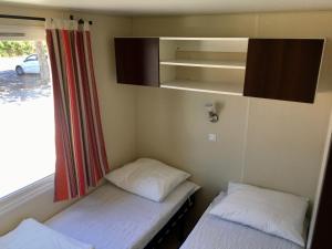 twee bedden in een kleine kamer met een raam bij Mobile Homes Argeles sur mer 3 bedroom in Argelès-sur-Mer