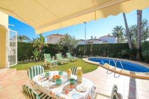 a patio with a table and chairs and a pool at Oliva Nova QL by CARLOSFERIEN in Oliva