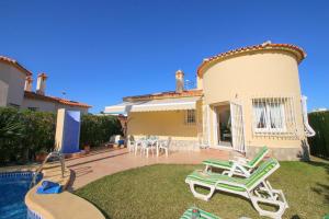 a house with a yard with chairs and a pool at Oliva Nova QL by CARLOSFERIEN in Oliva