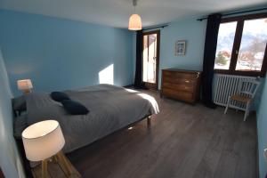 a blue bedroom with a bed and a table and chairs at Le Vallon des âmes - Large house for 15 people in Roubion in Névache