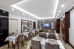 a restaurant with white tables and chairs and a flat screen tv at Ferman Hilal Hotel-Special Category in Istanbul
