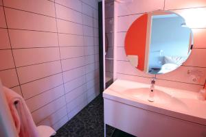 Baño rosa con lavabo y espejo en Hôtel Vulcain, en LʼHorme