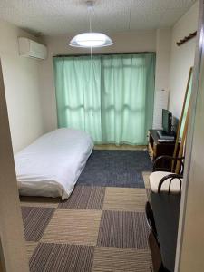 a room with a bed and a desk and a television at 202 Uzumasa Free Wi-Fi & 2Bike in Sagano