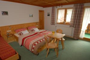 a bedroom with a bed with a table and a desk at Landhaus Bergleben in Oberstdorf