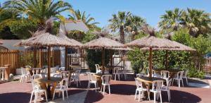 un grupo de mesas y sillas con sombrillas en Camping La Croix du Sud, en Le Barcarès