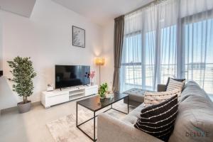 uma sala de estar com um sofá e uma televisão em Ideal 1BR at The Pulse Residence Icon A1 Dubai South by Deluxe Holiday Homes em Dubai