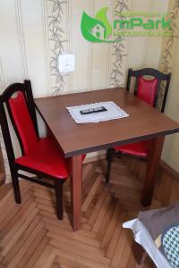 drewniany stół z dwoma czerwonymi krzesłami i pilotem w obiekcie Hostel Noclegi Chorzow w mieście Chorzów