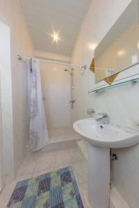 a white bathroom with a sink and a shower at Семейный отель "Виноградный" in Sochi