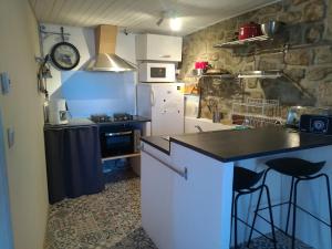 a kitchen with a stove and a counter with stools at gîte de la garde in Prévenchères