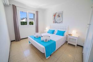 a bedroom with a bed with blue pillows and a window at Villa Diana in Port d'Alcudia