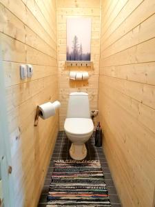 a small bathroom with a toilet and a rug at Self Check-in Sauna Cabin next to Hiking Trails in Kärde