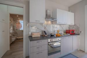 una cucina con armadi bianchi e forno a microonde rosso di Babyaccommodation Family Green a Pietra Ligure