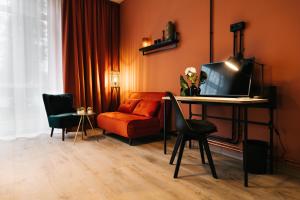 a living room with a couch and a desk with a television at Freilich am See - Gästezimmer in Strausberg