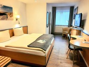 a hotel room with a bed and a desk at Hotel Pellmühle in Jever