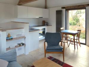 a kitchen with white cabinets and a table and chairs at High Cogges Farm Holiday Cottages - The Granary in Witney
