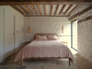 a bedroom with a bed in a brick wall at High Cogges Farm Holiday Cottages - The Granary in Witney