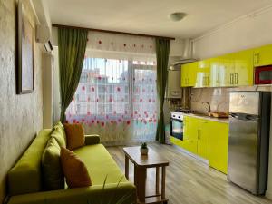 sala de estar con sofá verde y armarios amarillos en Apartament Summerland Mamaia Nord, en Mamaia