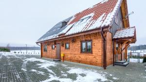 ein Holzhaus mit einem schneebedeckten Dach in der Unterkunft Sielski Spokój Dom z bali Apartamenty całoroczne in Gietrzwałd