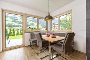 a dining room with a table and chairs and windows at Apart Jasmin in Ramsau