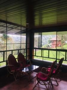 a room with chairs and a table and windows at Vythiri Misty Wind Holiday Homes in Vythiri