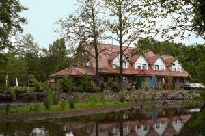 une maison à côté d'une rivière avec des canards dans l'eau dans l'établissement Hotel MyLord, à Soltau