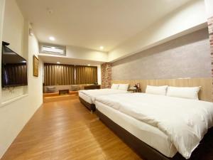 una camera d'albergo con due letti e una televisione di Taichung Old F Hotel a Taichung