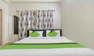 ein Schlafzimmer mit einem weißen Bett mit grünen und gelben Kissen in der Unterkunft Treebo Trend Alankar Hoshangabad Road in Bhopal