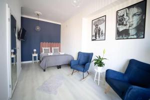 a bedroom with a bed and two blue chairs at Alton Aleje Apartment 3 in Warsaw