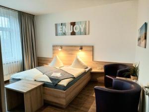 ein Hotelzimmer mit einem Bett, einem Schreibtisch und Stühlen in der Unterkunft Hotel Pellmühle in Jever