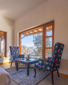 um quarto com duas cadeiras, uma mesa e uma janela em Seclude Ramgarh Willows em Rāmgarh