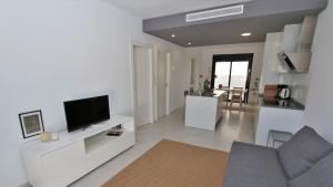 sala de estar con TV en una pared blanca en Luxe appartement met 2 badkamers / zee / zwembad, en Lo Pagán