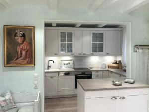 a kitchen with white cabinets and a painting of a woman at Haus Anholt in Timmendorfer Strand