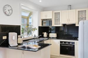 a kitchen with white cabinets and a clock on the wall at Cliff Haven Retreat in Katoomba