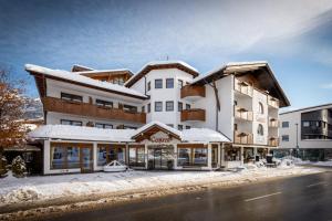 ein großes weißes Gebäude mit Schnee auf dem Boden in der Unterkunft Hotel Central in Seefeld in Tirol