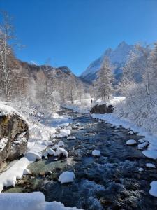 a river covered in snow with mountains in the background at Chalet 12 Cerfs in Evolène