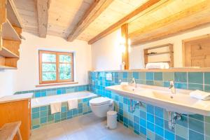 baño de azulejos azules con 2 lavabos y aseo en Landhaus Buchenberg, en Rettenberg