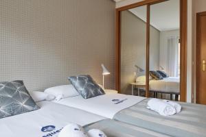 two beds in a room with a mirror at Koral - Basque Stay in San Sebastián