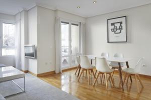 una sala de estar blanca con mesa y sillas en Koral - Basque Stay, en San Sebastián