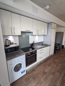 a kitchen with white cabinets and a dishwasher at Middlehaven Studio in Middlesbrough