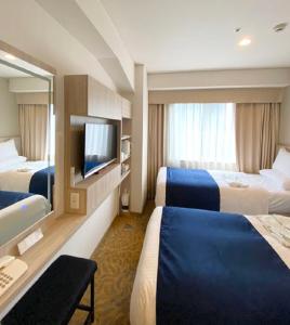 a hotel room with two beds and a flat screen tv at Hotel Rose Garden Shinjuku in Tokyo
