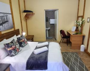 um quarto com uma grande cama branca e uma casa de banho em Houtgerus Gastehuis/Guesthouse em Olifantshoek